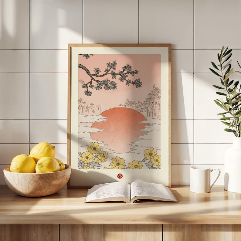 Puede incluir: Una impresi&oacute;n enmarcada de una ilustraci&oacute;n de estilo japon&eacute;s que representa una puesta de sol sobre una masa de agua con una rama de &aacute;rbol con hojas en la esquina superior izquierda. La impresi&oacute;n est&aacute; rodeada de un marco de madera claro y se encuentra sobre una superficie de madera.