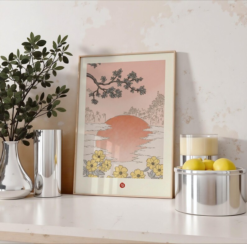Puede incluir: Una impresi&oacute;n enmarcada de una ilustraci&oacute;n de estilo japon&eacute;s que representa una puesta de sol sobre una masa de agua con una rama de &aacute;rbol con flores en primer plano. La impresi&oacute;n tiene una gama de colores rosa y melocot&oacute;n con flores amarillas en la esquina inferior derecha.