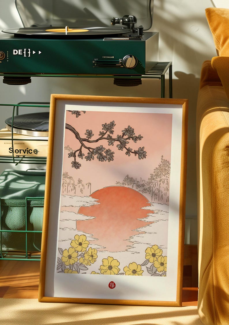 Puede incluir: Una impresi&oacute;n enmarcada de una ilustraci&oacute;n de inspiraci&oacute;n japonesa que presenta una puesta de sol estilizada sobre un horizonte urbano con una rama de cerezos en flor en primer plano. La impresi&oacute;n tiene un fondo melocot&oacute;n y flores amarillas.