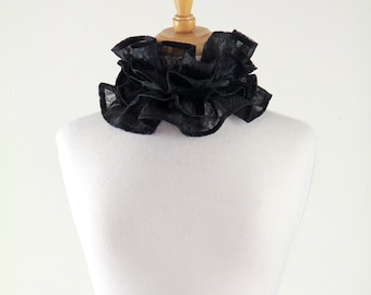 May include: A black lace choker with ruffled edges, displayed on a white mannequin.