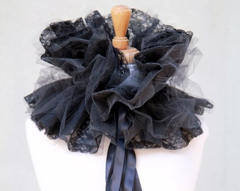 May include: A black lace and tulle collar with a black satin ribbon tie. The collar is ruffled and has a vintage style.