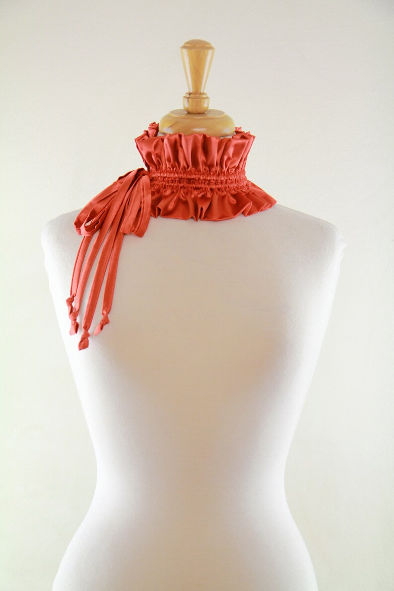 May include: A red ruffled collar with a long, thin tie. The collar is made of a soft, silky fabric and is perfect for adding a touch of elegance to any outfit.