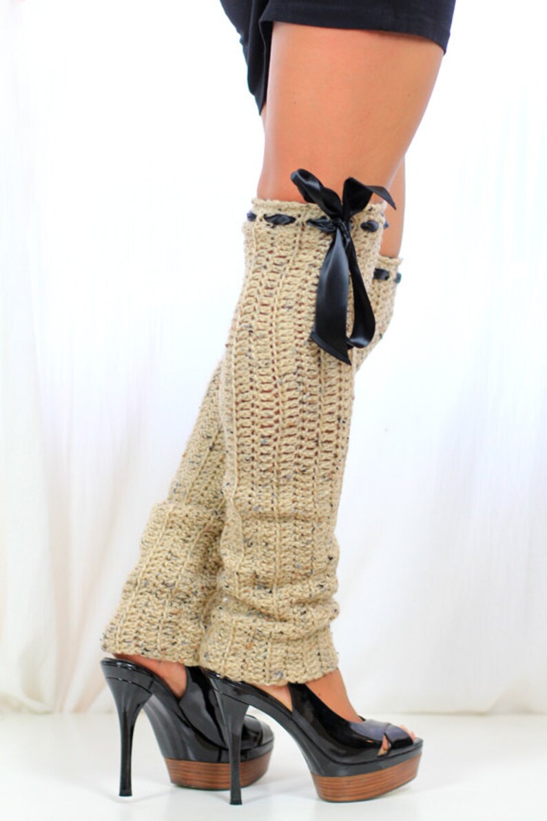 May include: Beige crochet leg warmers with a black satin ribbon bow. The leg warmers are worn with black platform heels.
