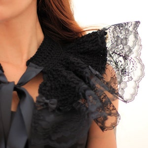 Puede incluir: Un collar de crochet negro con ribete de encaje y una cinta de sat&eacute;n negra atada en un lazo. El collar se lleva sobre una blusa negra.