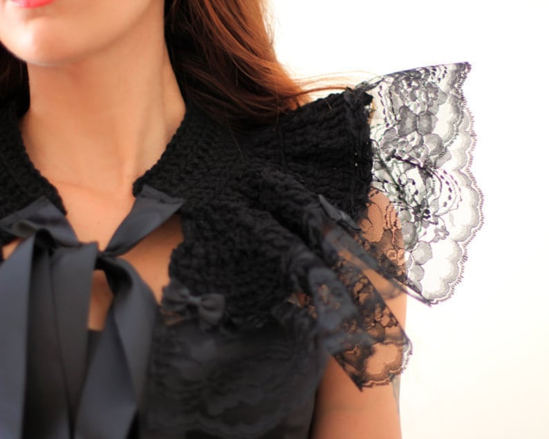 Puede incluir: Un collar de crochet negro con ribete de encaje y una cinta de sat&eacute;n negra atada en un lazo. El collar se lleva sobre una blusa negra.