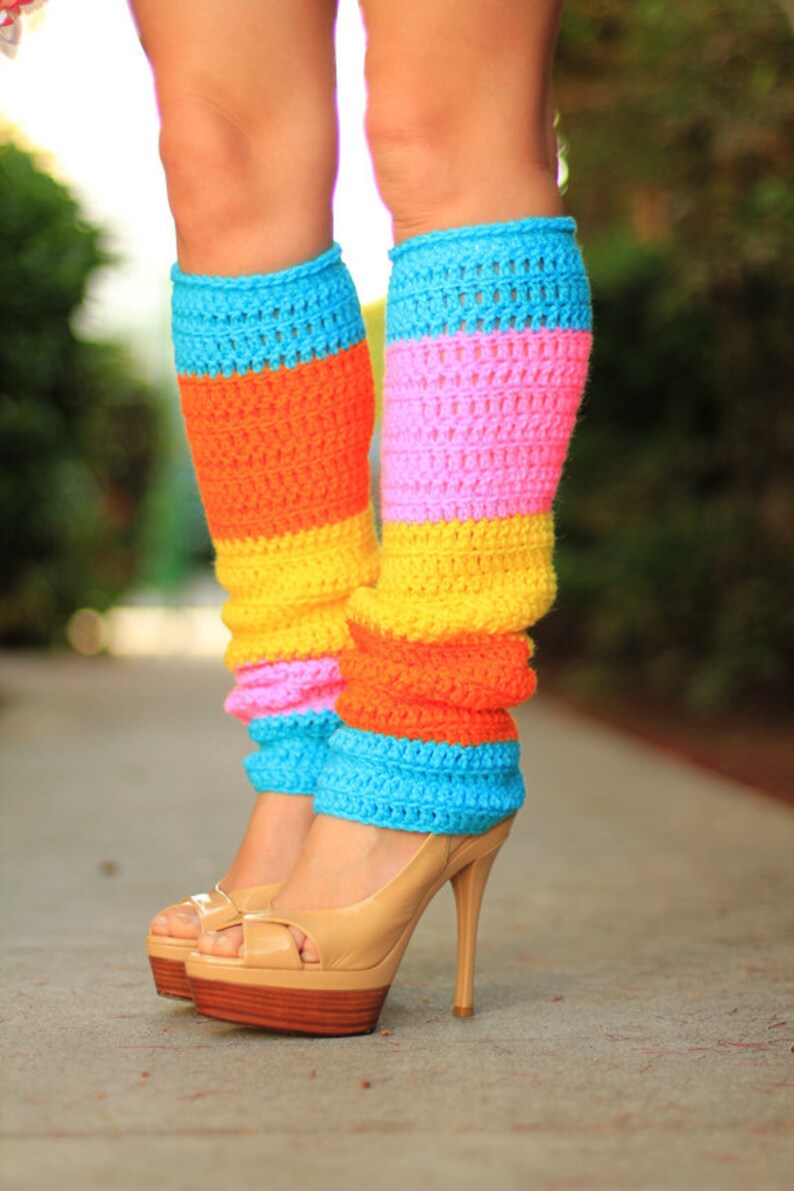 May include: A pair of colorful crocheted leg warmers with stripes of blue, pink, yellow, and orange. The leg warmers are worn with nude high-heeled shoes.