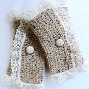May include: A pair of beige crocheted wrist warmers with white lace trim and white buttons.