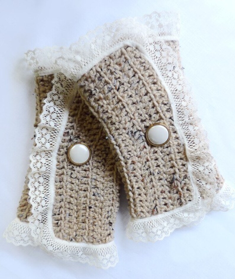 May include: A pair of beige crocheted wrist warmers with white lace trim and white buttons.