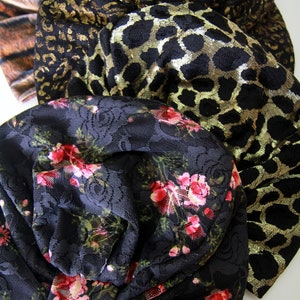 Puede incluir: Tres cintas para la cabeza de tela apiladas. La cinta superior es negra con estampado de leopardo dorado, la cinta del medio es negra con estampado de animal dorado y negro, y la cinta inferior es negra con estampado floral.