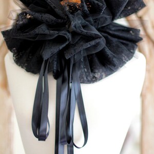 May include: A black lace collar with a ruffled design and long black satin ribbons.