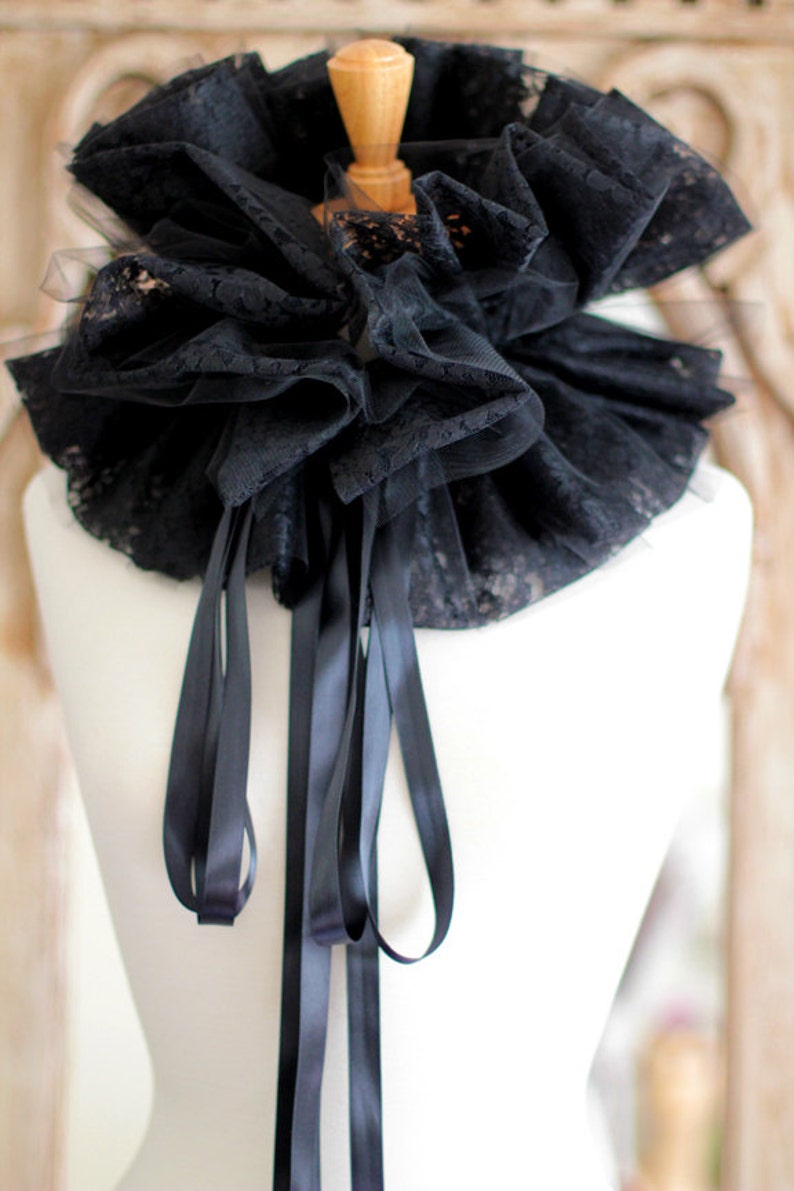 May include: A black lace collar with a ruffled design and long black satin ribbons.