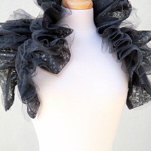 May include: A black lace collar with ruffles, displayed on a white mannequin.