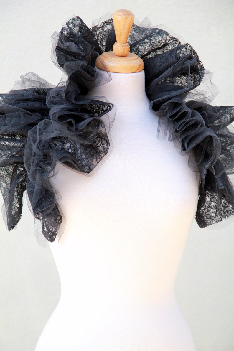 May include: A black lace collar with ruffles, displayed on a white mannequin.
