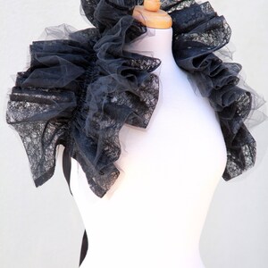 May include: A black lace collar with ruffles, displayed on a white mannequin.