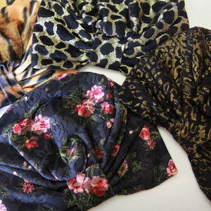 Puede incluir: Cuatro diademas de tela diferentes en una variedad de patrones. Una diadema es negra con un patr&oacute;n floral, otra es negra con un estampado de leopardo dorado, otra es negra con un estampado de leopardo dorado y negro, y la &uacute;ltima es marr&oacute;n y naranja con un estampado de tigre.