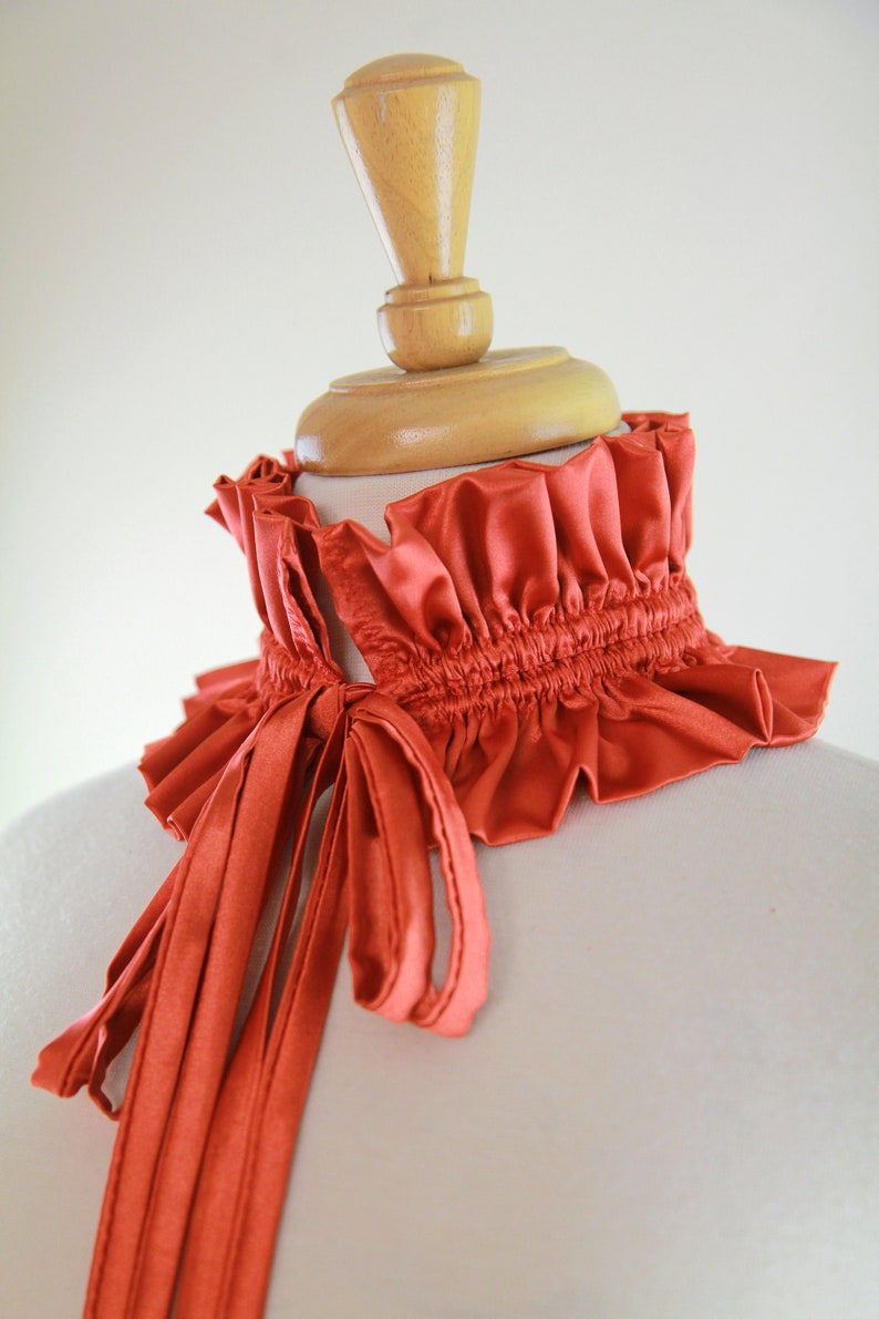 May include: A rust-colored satin choker with a gathered ruffle and a long, tied bow.