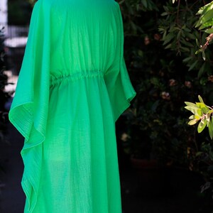 Puede incluir: Un vestido kaft&aacute;n verde brillante y fluido con cintura fruncida. El vestido est&aacute; hecho de una tela ligera y tiene un corte holgado.