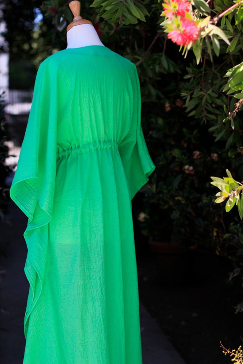 Puede incluir: Un vestido kaft&aacute;n verde brillante y fluido con cintura fruncida. El vestido est&aacute; hecho de una tela ligera y tiene un corte holgado.