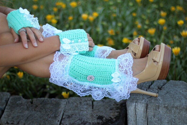 May include: Mint green crochet leg warmers with white lace trim and a rhinestone embellishment. The leg warmers are worn with high-heeled sandals.