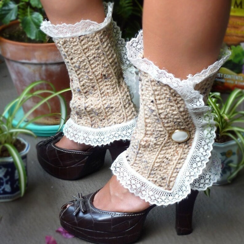 May include: Beige knitted leg warmers with white lace trim and a white button. The leg warmers are worn with brown heeled shoes.