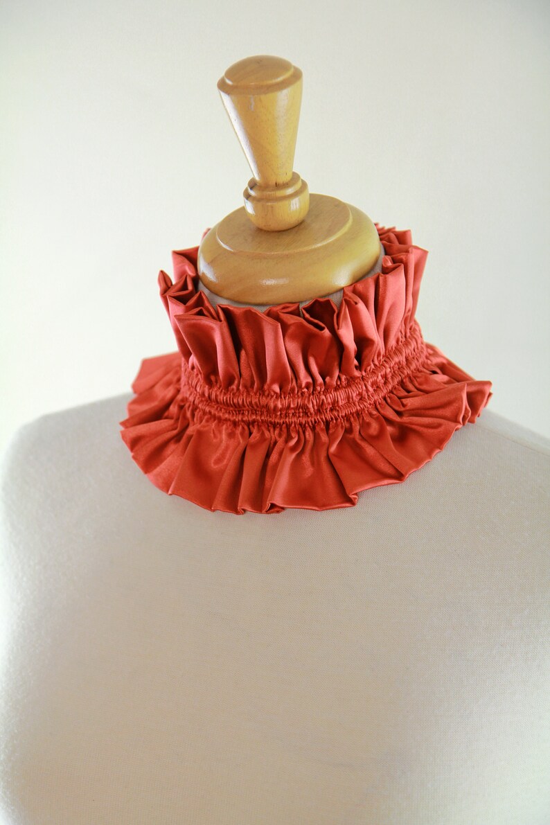 May include: A rust-colored ruffled fabric collar on a dress form.