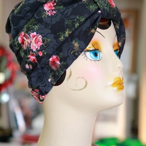 Puede incluir: Un turbante de encaje negro con estampado floral rosa, usado por un maniqu&iacute; con ojos azules y sombra de ojos amarilla.