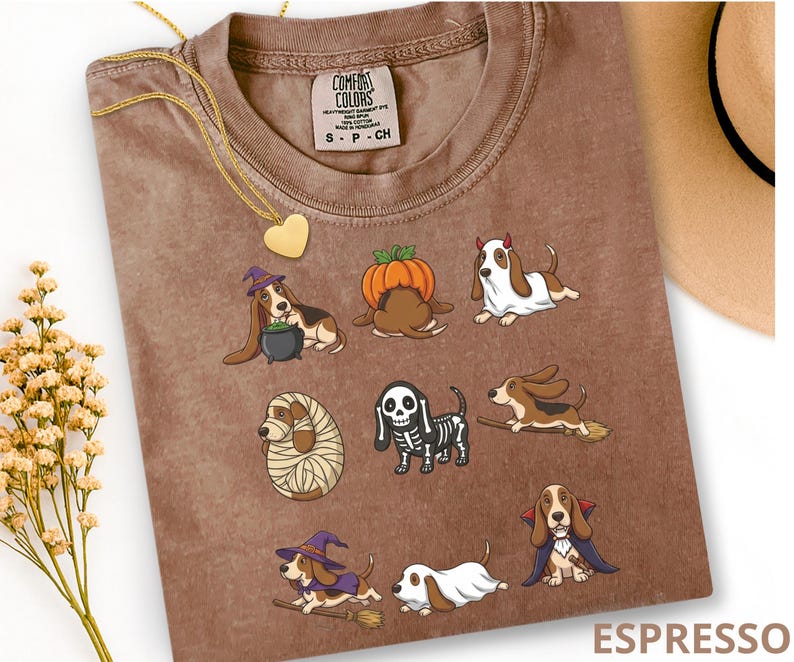 Pu&ograve; includere: Una t-shirt color espresso con una stampa grafica di otto cani Basset Hound in vari costumi di Halloween, tra cui una strega, una zucca, un fantasma, una mummia, uno scheletro e un vampiro. La maglietta ha un'etichetta del marchio Comfort Colors.
