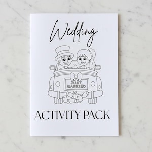 Può includere: Un pacchetto di attività per matrimoni bianco con testo e illustrazioni neri. La copertina presenta un cartone animato di sposi in un'auto con un cartello "Just Married". Le parole "Wedding" e "ACTIVITY PACK" sono anch'esse stampate.