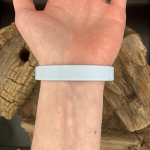 Puede incluir: Una pulsera de silicona azul claro en la mu&ntilde;eca de una persona.