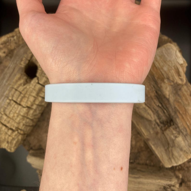 Puede incluir: Una pulsera de silicona azul claro en la mu&ntilde;eca de una persona.