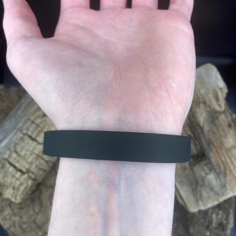 Pu&ograve; includere: Un braccialetto in silicone nero al polso.