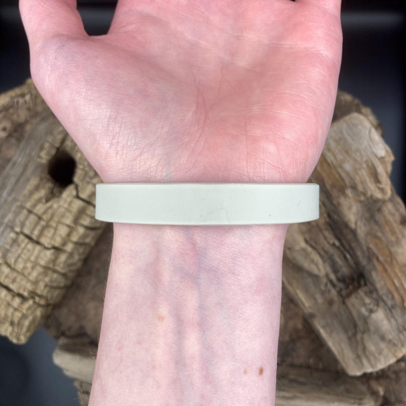 Puede incluir: Una pulsera de silicona verde claro en la mu&ntilde;eca de una persona.