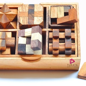 May include: A wooden puzzle set featuring various geometric shapes and interlocking pieces. The set includes a star-shaped puzzle, cross-shaped puzzles, and other block puzzles, all stored in a wooden box. A separate square wooden piece is also included.