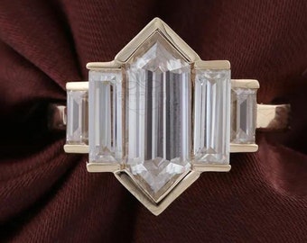 May include: A gold engagement ring with a large, clear, rectangular-shaped diamond in the center. The diamond is surrounded by four smaller, clear, rectangular-shaped diamonds.
