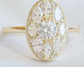 May include: A yellow gold ring featuring an oval-shaped cluster head. The centre is set with a round brilliant-cut diamond, surrounded by eight marquise-cut diamonds arranged in a halo pattern, all secured within a milgrain-edged gold setting.