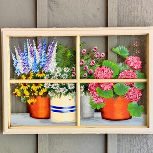 May include: A rectangular window frame with four panes featuring a hand-painted scene of potted flowers. The left side shows blue and yellow flowers in orange and cream pots. The right side displays pink hydrangea-like blooms in orange pots.