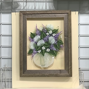 May include: A framed painting of a bouquet of purple and white flowers in a clear glass vase. The flowers are arranged in a rustic wooden frame.