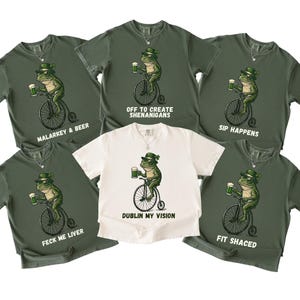 May include: A collection of green and white t-shirts featuring a cartoon frog riding a bicycle and holding a beer mug. Each shirt has a different phrase, including "Malarkey & Beer" and "Dublin My Vision."