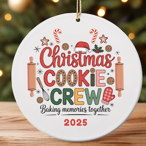 May include: White ceramic Christmas ornament with the text "Christmas COOKIE CREW Baking memories together 2025." The ornament features candy canes, cookies, a Santa hat, rolling pins, and a mitten.