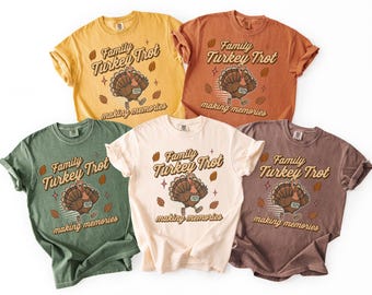 May include: Five t-shirts in various colours, featuring the text "Family Turkey Trot making memories" and a cartoon turkey. The shirts are yellow, orange, green, cream, and brown. The design includes autumn leaves and stars.