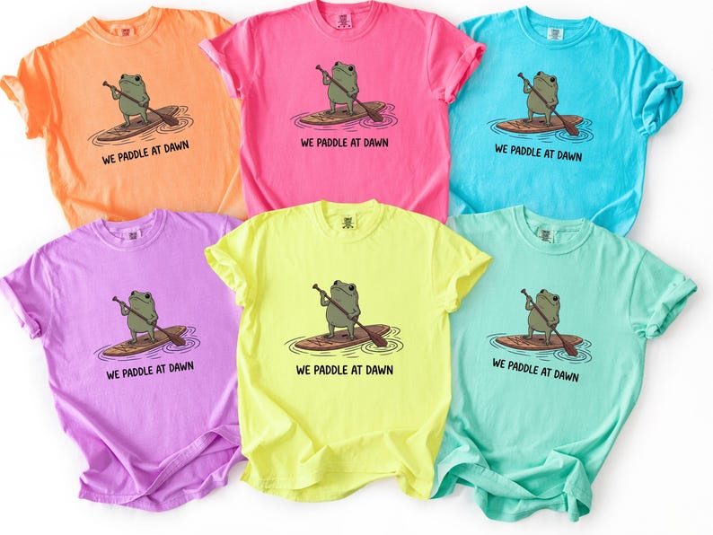 Pu&ograve; includere: Sei magliette a maniche corte con girocollo in vivaci colori neon tra cui arancione, rosa, blu, viola, giallo e verde menta. Ogni maglietta presenta una grafica di una rana verde su una tavola da paddle con il testo WE PADDLE AT DAWN stampato.