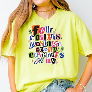 May include: A neon yellow short-sleeve t-shirt featuring a multi-colored graphic print with the text "four corners, postage stamp, coveralls oh my" in a collage style. The design includes various dollar sign symbols and small star accents.