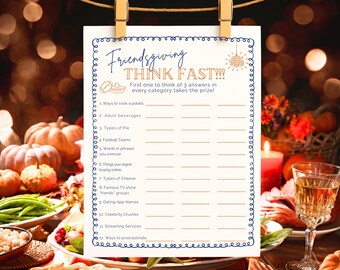 May include: A printable Friendsgiving game card with a blue border, hanging from a clothesline. The card features the text "Friendsgiving THINK FAST!!!" and prompts for answers in categories like "Ways to cook a potato" and "Types of Pie."