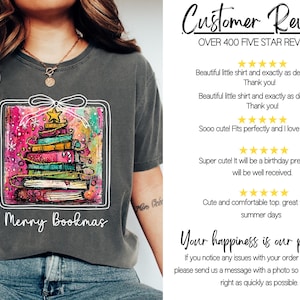 May include: Dark gray t-shirt featuring a colorful graphic of a Christmas tree made of books, with a star on top. The text "Merry Bookmas" is below the graphic.