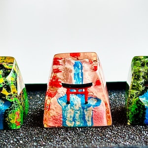 Puede incluir: Tres teclas personalizadas con un diseño de cascada japonesa. Cada tecla presenta una cascada, un torii rojo y un exuberante follaje verde. Las teclas están sobre un fondo oscuro.