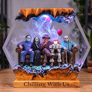 May include: A hexagonal resin and wood display featuring five horror movie character figurines sitting on a brown sofa. The base is engraved with the text "Chilling With Us" and the scene is filled with swirling blue and purple smoke effects.
