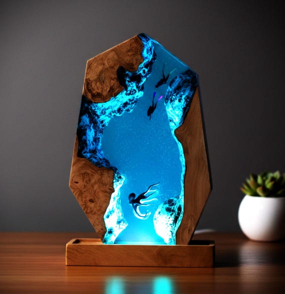 Fully custom epoxy resin lamp with octopus and scuba divers frozen mid-dive in glowing wood — the personalization angle makes it a genuinely rare gift for a diver.