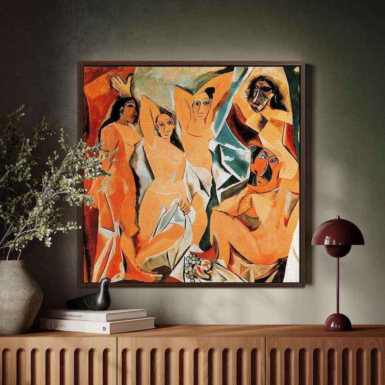 Puede incluir: Una pintura abstracta enmarcada que presenta figuras desnudas en tonos naranja, rojo y azul. La obra de arte tiene un marco marr&oacute;n oscuro y se exhibe sobre un mueble de madera. Tambi&eacute;n se ven una l&aacute;mpara burdeos y objetos decorativos.