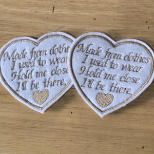 May include: Two white heart-shaped patches with gold trim and embroidered text. The text reads "Made from clothes I used to wear, Hold me close, I'll be there." A small gold heart is embroidered at the bottom.