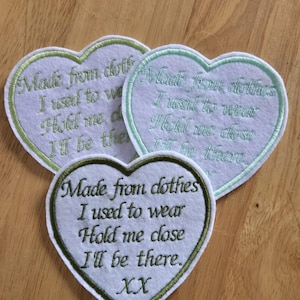 May include: Three white felt heart-shaped patches with green embroidered edges. Each patch has the text "Made from clothes I used to wear Hold me close I'll be there." The bottom patch also has the text "XX" embroidered on it.